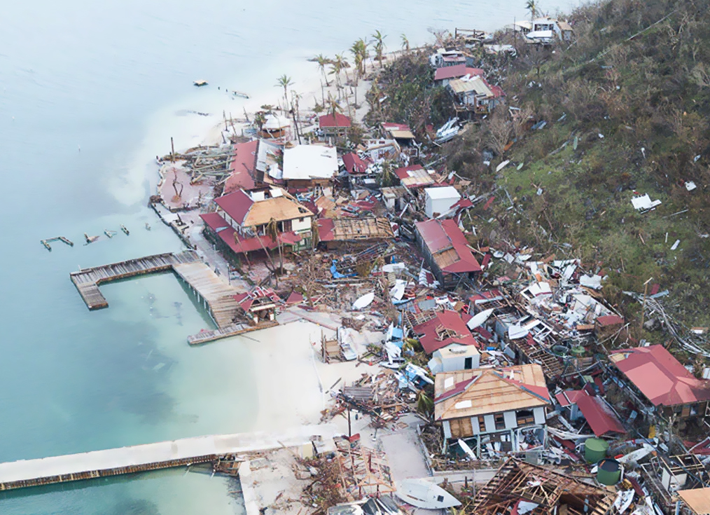 a destroyed houses on a hill by water