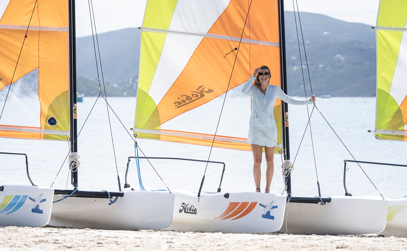 a woman standing on a sailboat on a beach