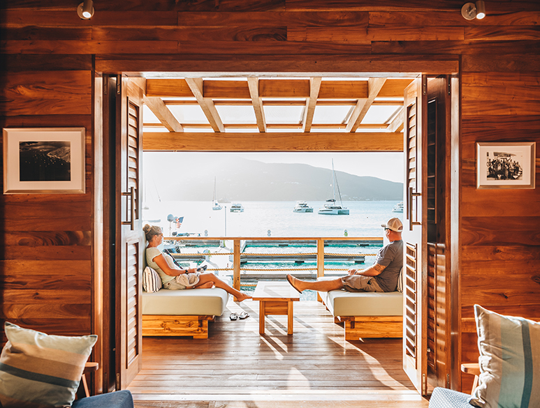 a couple sitting on couches in a room with a view of the water