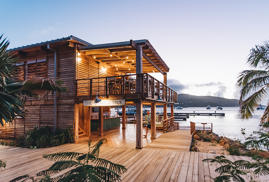 a wooden building with a deck and a dock with boats in the water