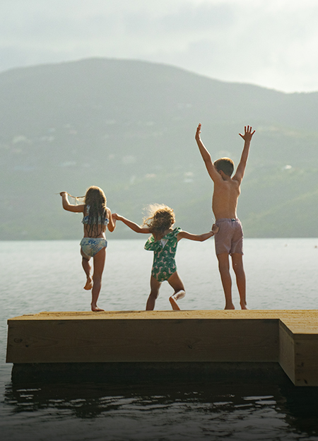 a group of children jumping on a dock