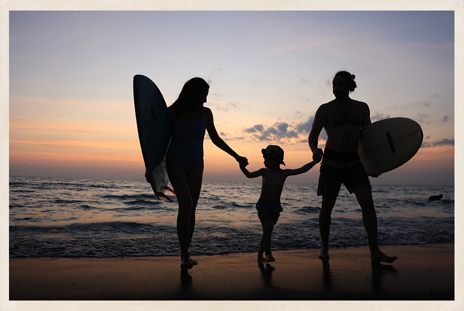a silhouette of a man and woman holding hands and a child walking on a beach