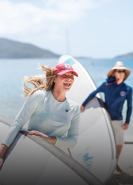 a woman holding a surfboard and smiling