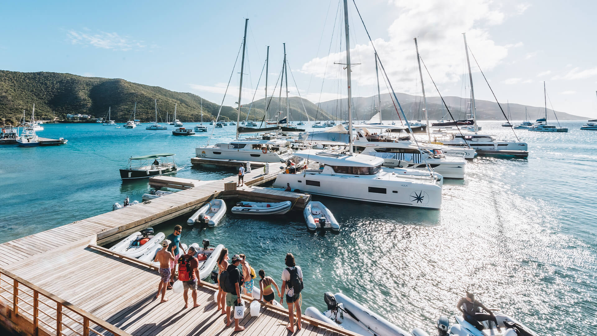 a group of people standing on a dock with boats in the water