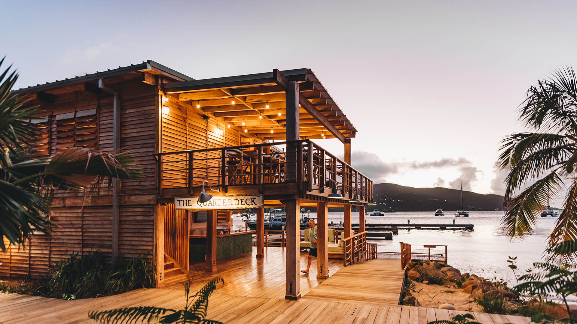 a building with a deck and a dock with boats in the water