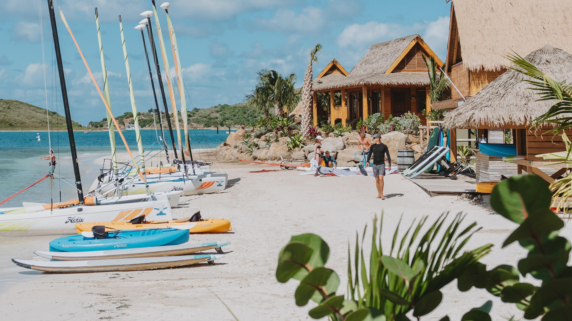 a group of people on a beach with kayaks and boats