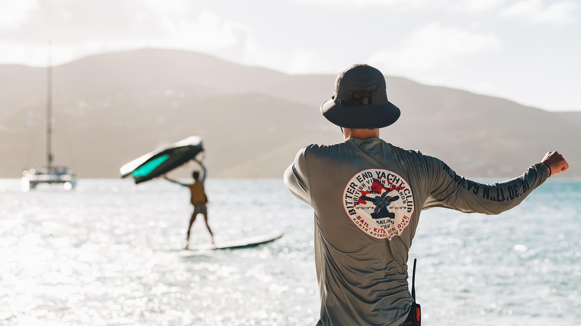 a man standing on a beach with a surfboard and a man on a surfboard