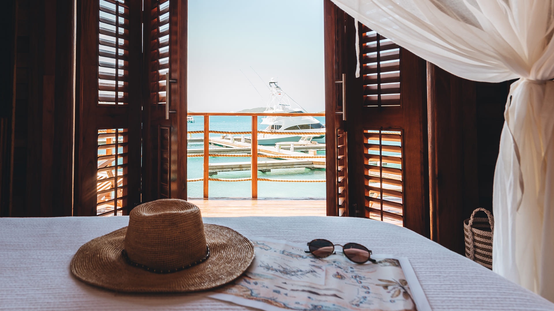a hat and sunglasses on a table with a boat in the background