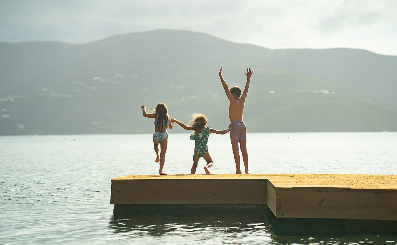 a group of kids jumping on a dock