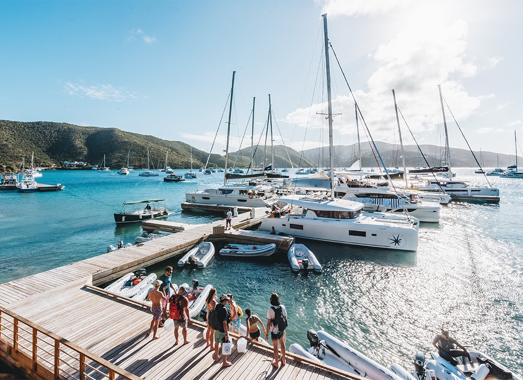 a group of people standing on a dock with boats in the water
