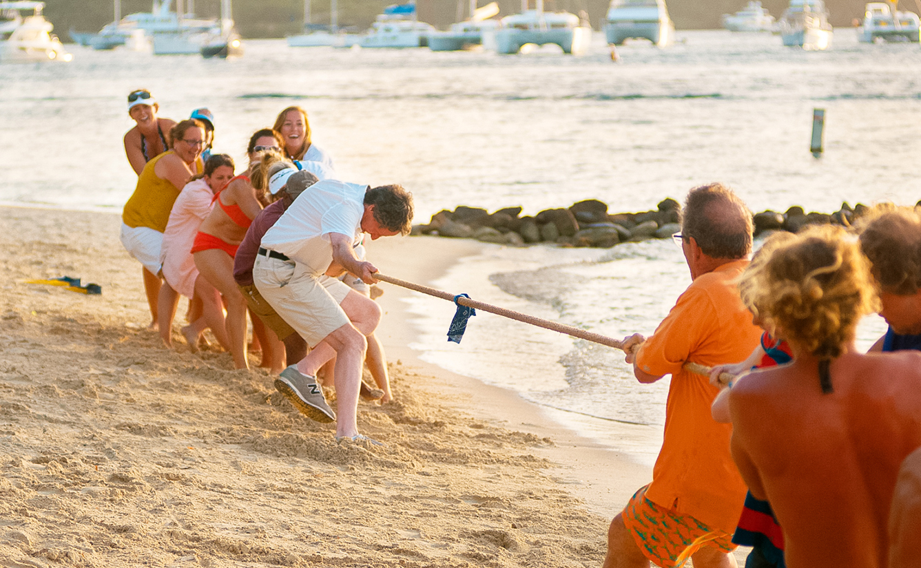 a group of people pulling a rope on a beach