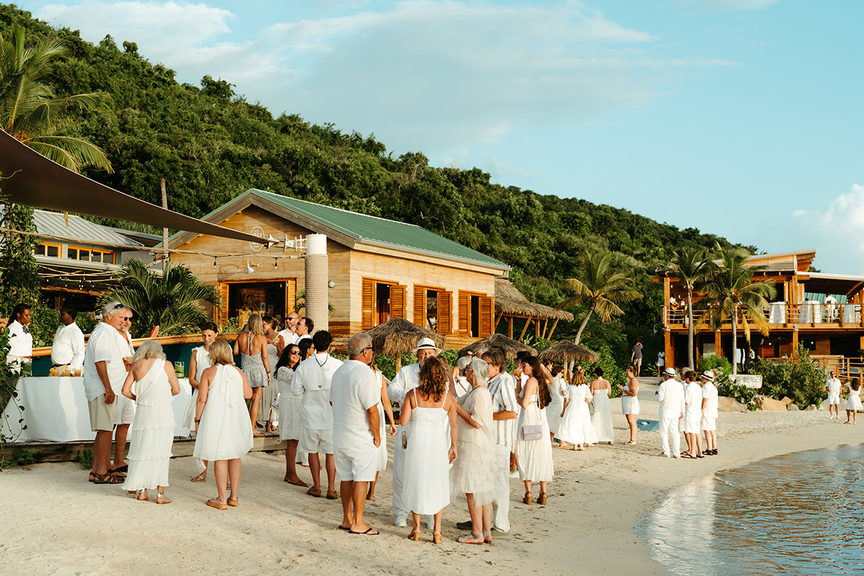a group of people in white dresses on a beach