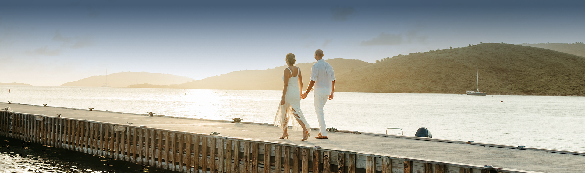 a man and woman holding hands walking on a dock