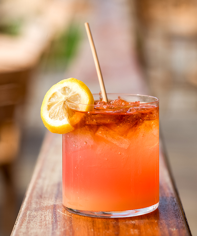 a glass of orange drink with a lemon slice and a straw