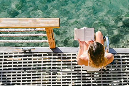 a woman sitting on a dock reading a book