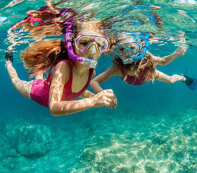 two girls wearing snorkeling gear underwater