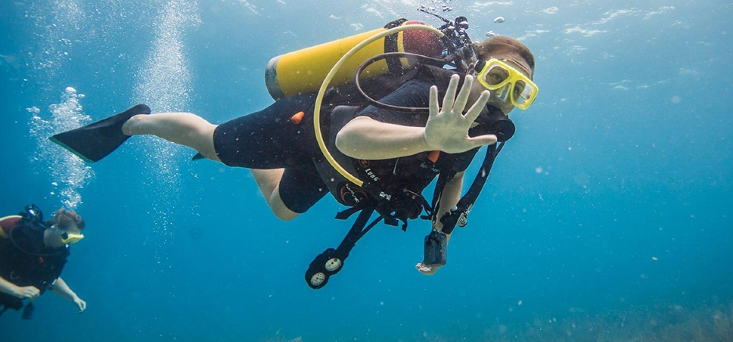 A diver explores a vibrant coral reef in the clear blue water of the North Sound