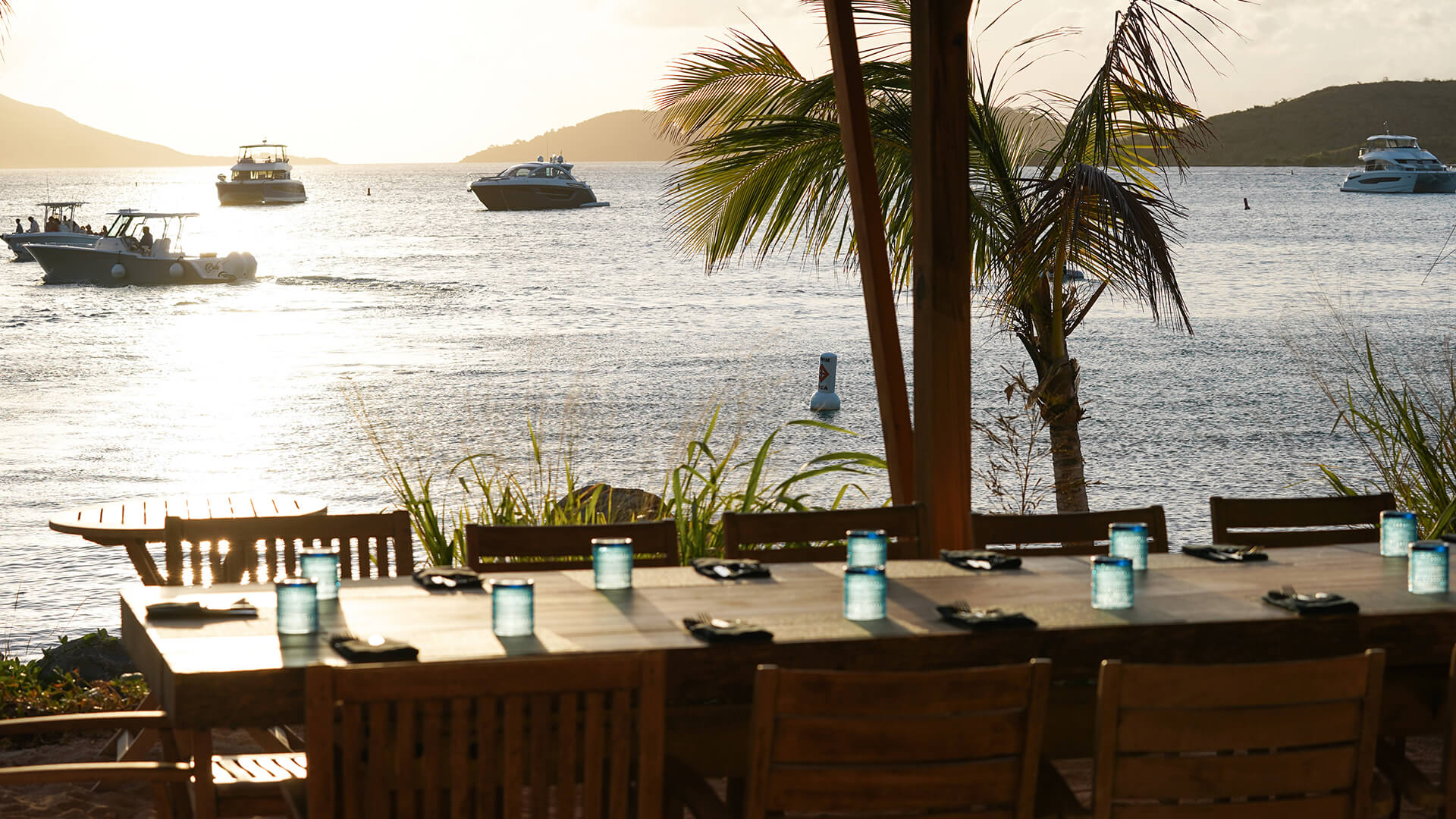 a table set up on a beach with a boat in the water