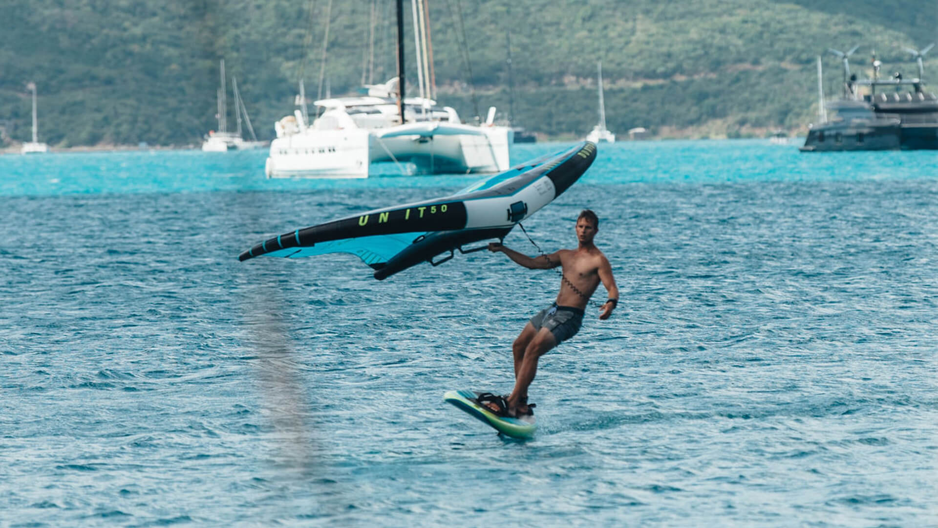 a man on a surfboard carrying a sailboat