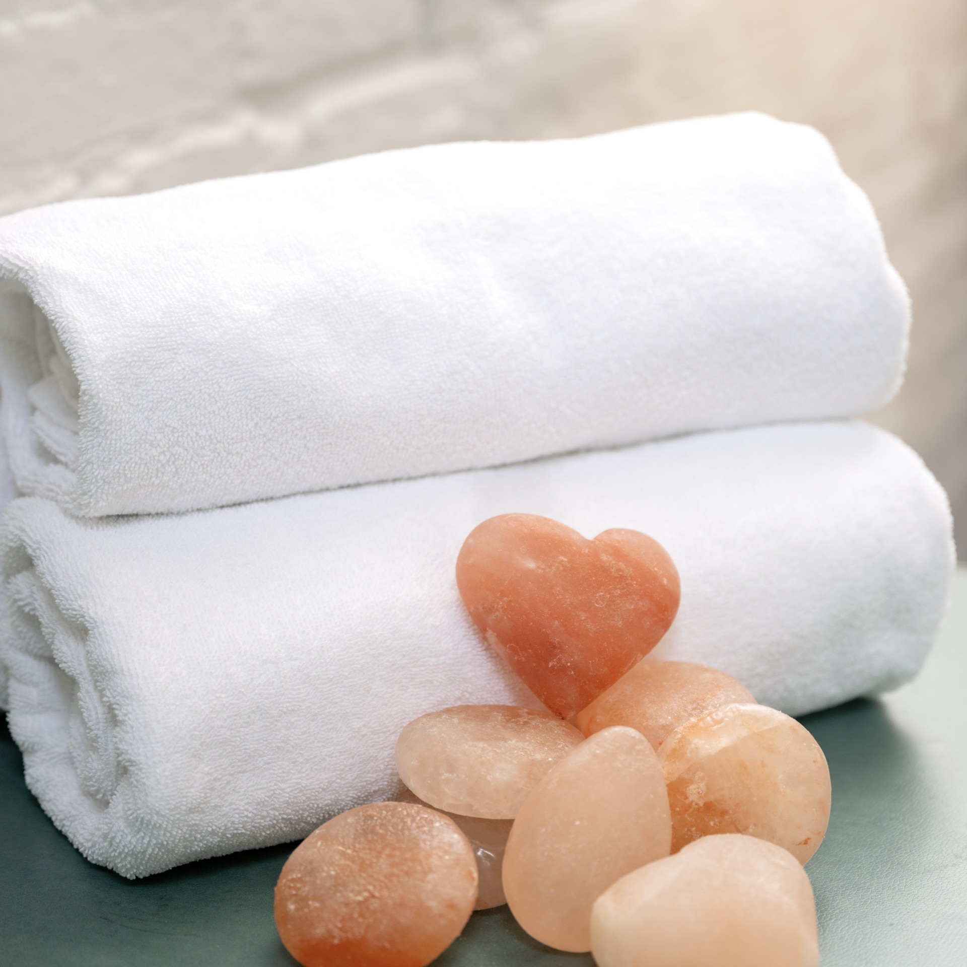 a stack of white towels and a heart shaped rock