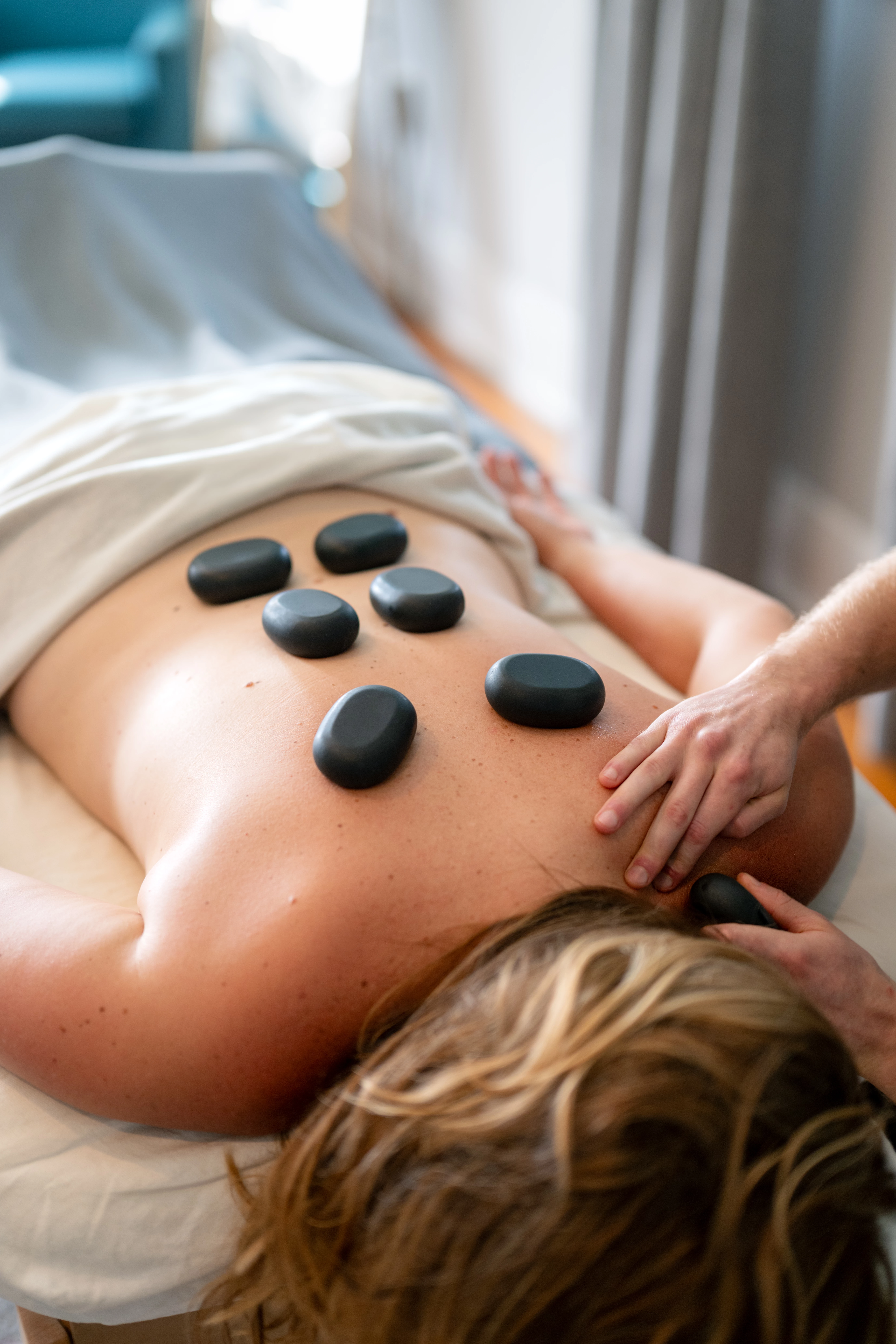 a person lying on a bed with a stone on their back