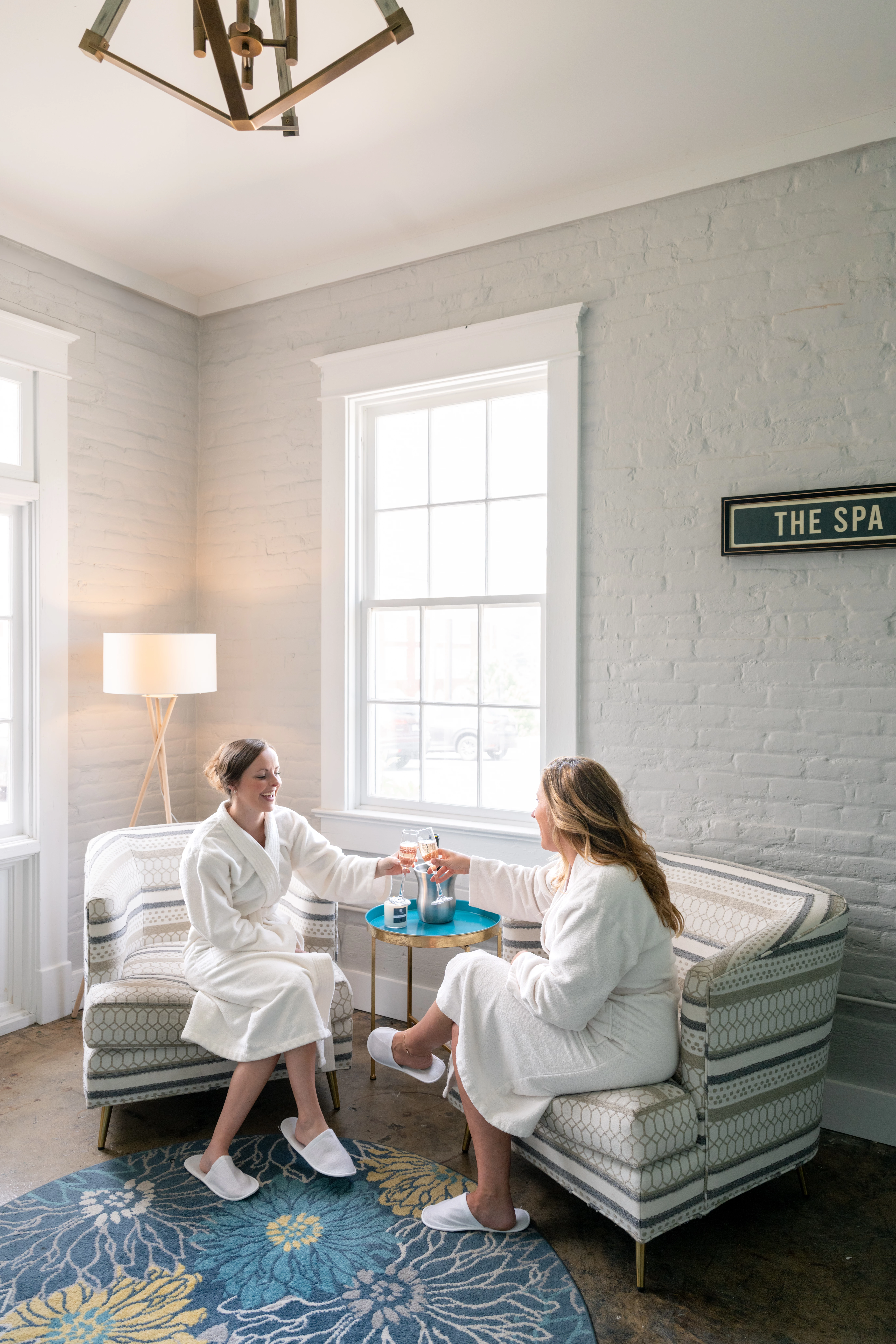 two women in white robes sitting in a room with a table and chairs