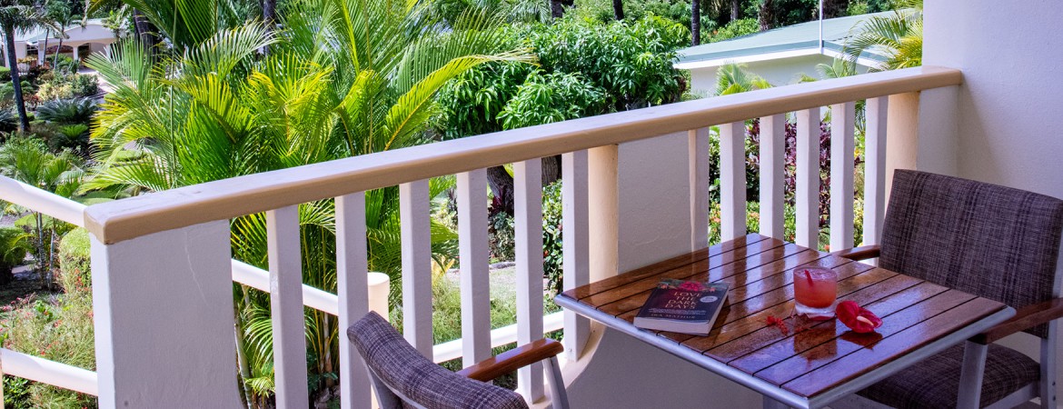a table with a book on it and a chair on a balcony with trees