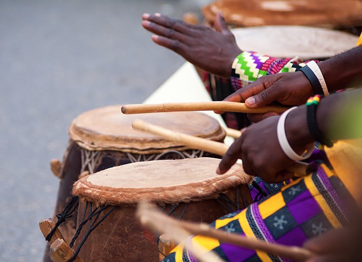 two people playing wooden drums with their hands and drum sticks