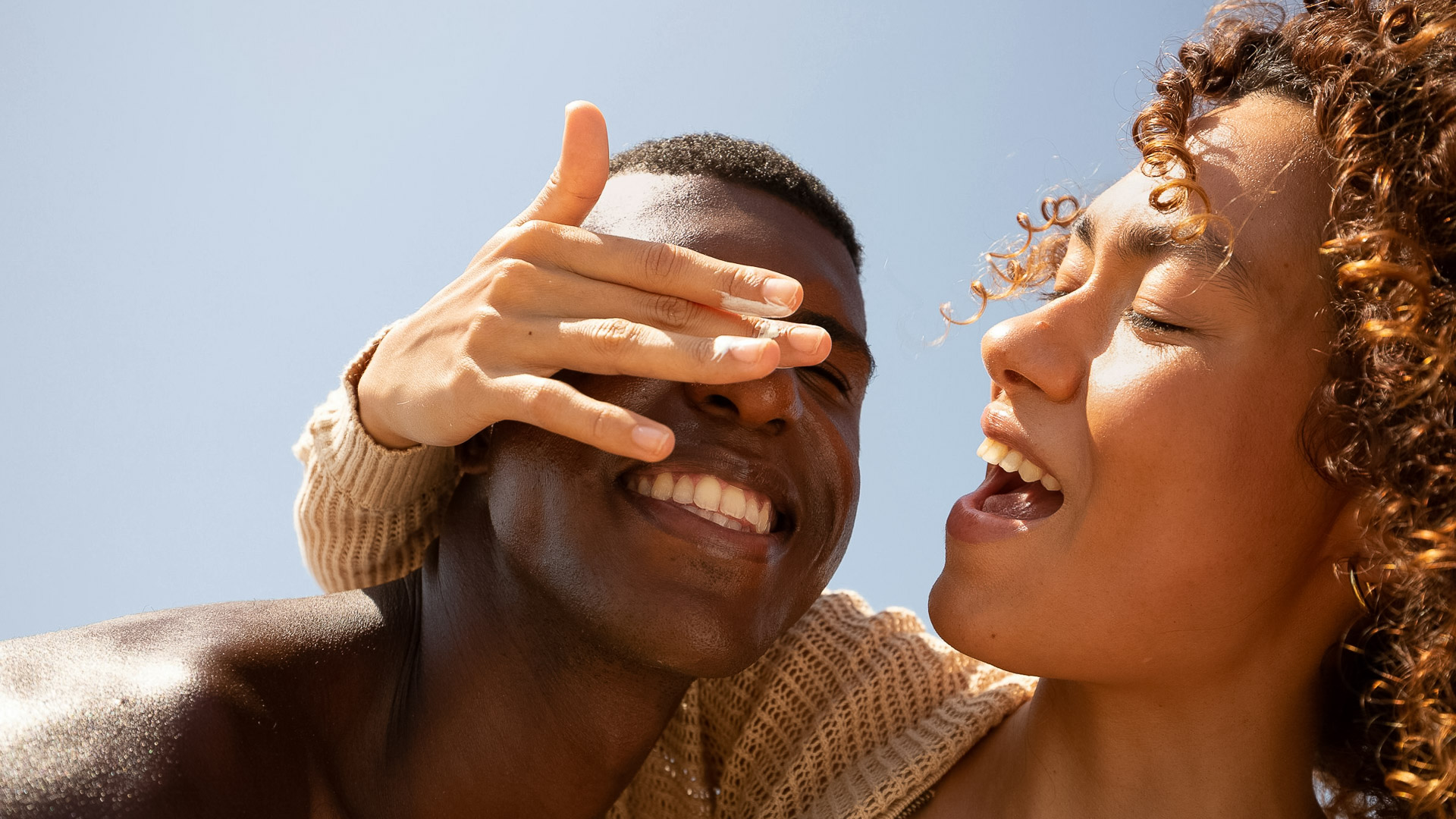 a man and woman smiling and covering eyes