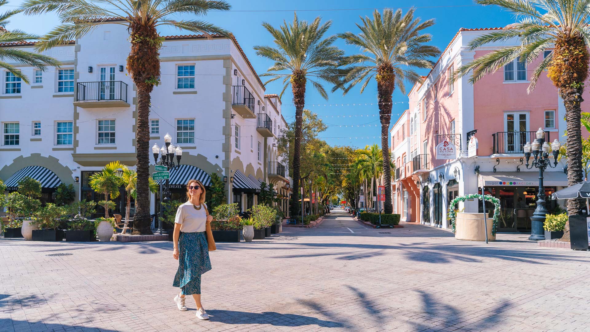 a woman standing in a street with palm trees and buildings