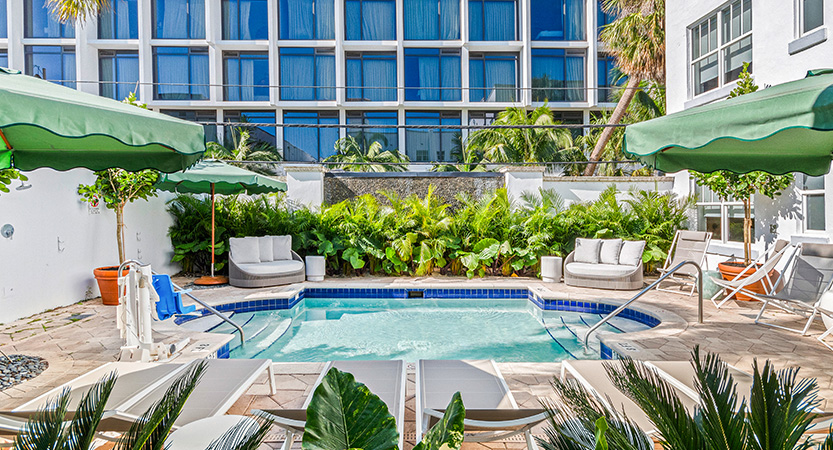 a pool with chairs and umbrellas in front of a building