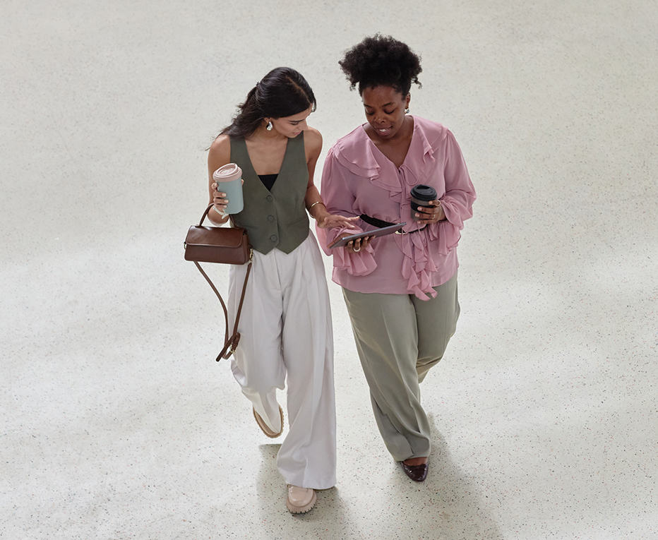 a woman walking with another woman holding a tablet