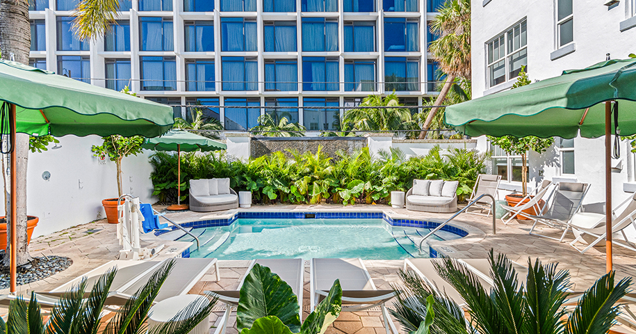a pool with chairs and umbrellas in front of a building