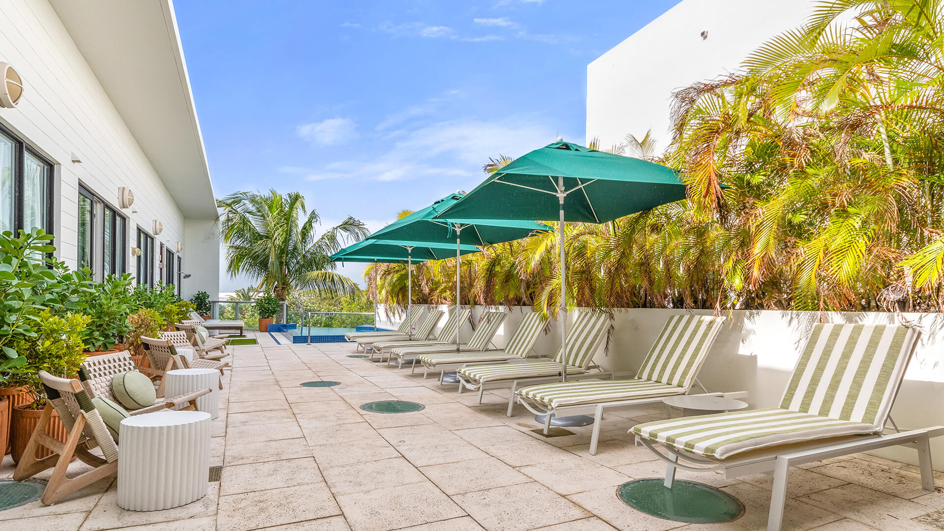 a group of lounge chairs and umbrellas on a patio