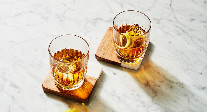 two glasses of alcohol on coasters