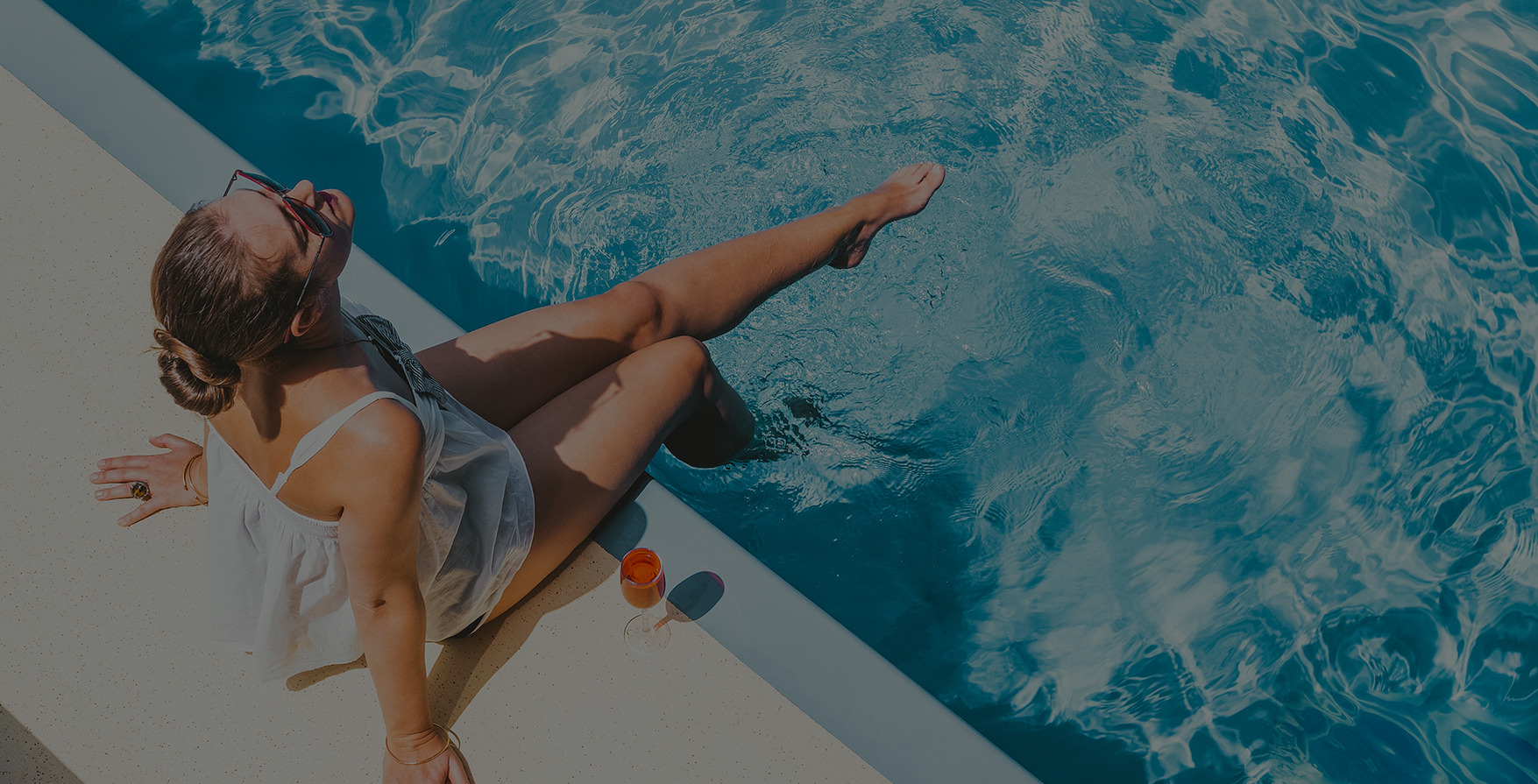 a woman sitting on a ledge near a pool