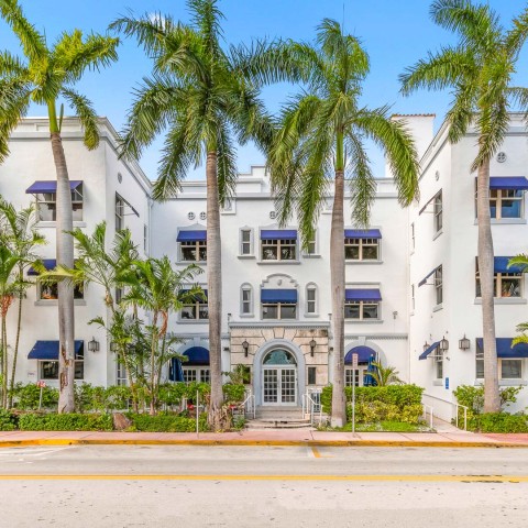 a building with palm trees and blue awnings