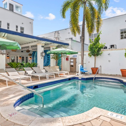 a pool with lounge chairs and umbrellas in front of a building