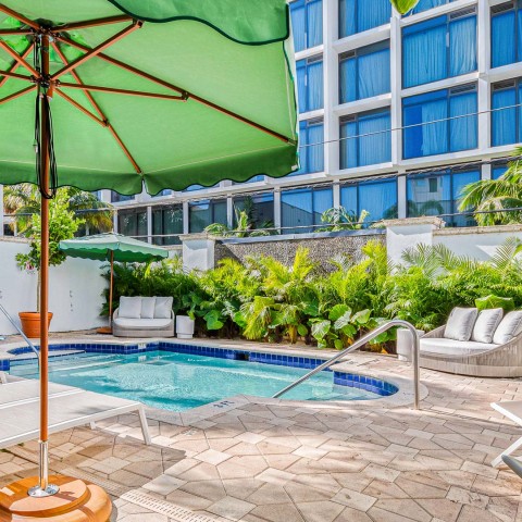 a pool with a green umbrella and chairs