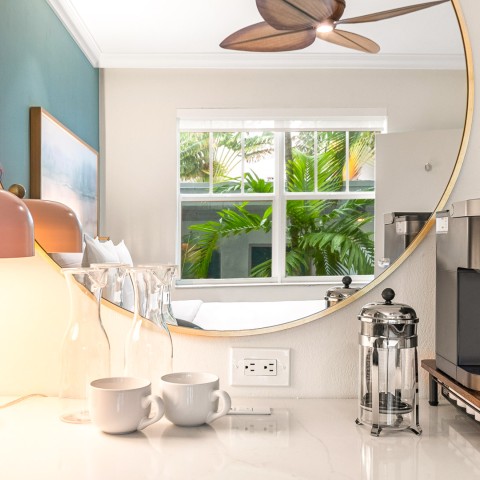 a mirror on a counter top with cups and coffee glasses