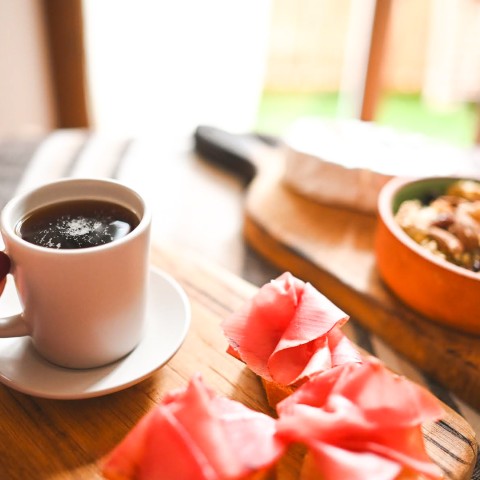 a hand holding a cup of coffee next to a bowl of food
