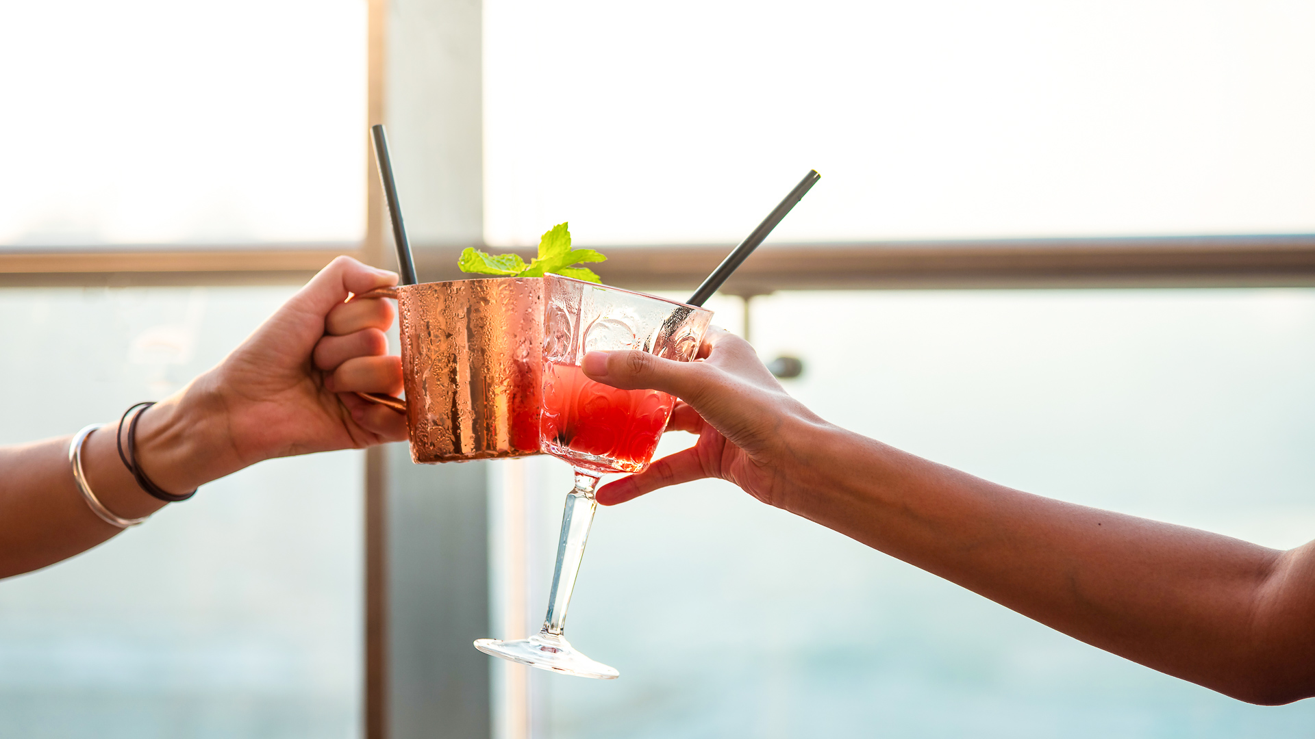 a pair of hands holding up a glass of drinks