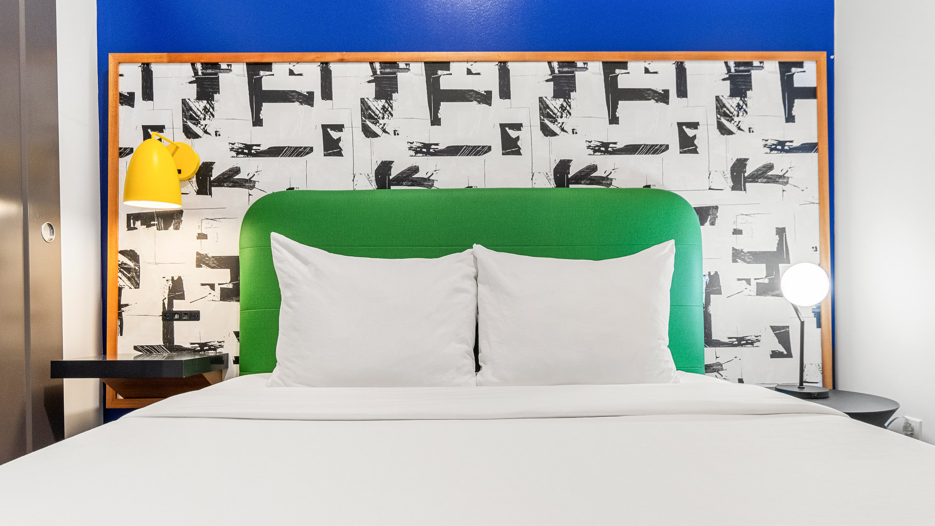 a bed with white pillows and green headboard