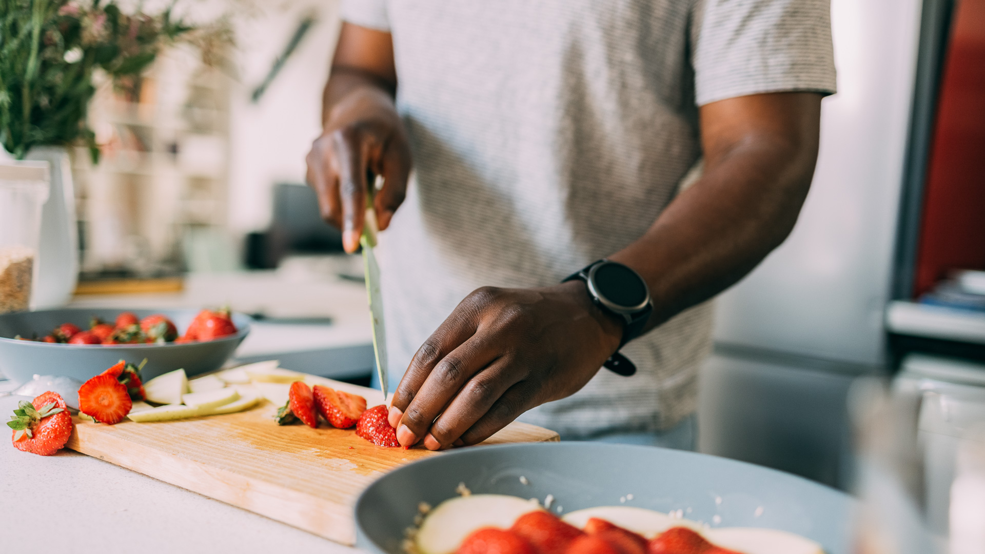 a person cutting strawberries on a cutting board