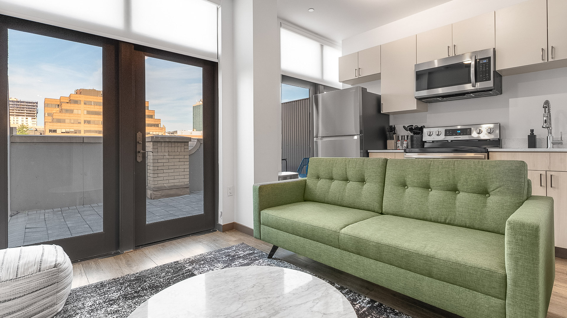 a living room with a green couch and a kitchen