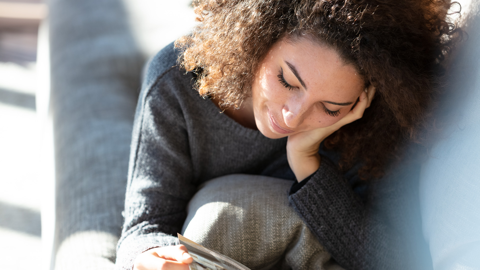 a woman sitting on a couch looking at a piece of paper