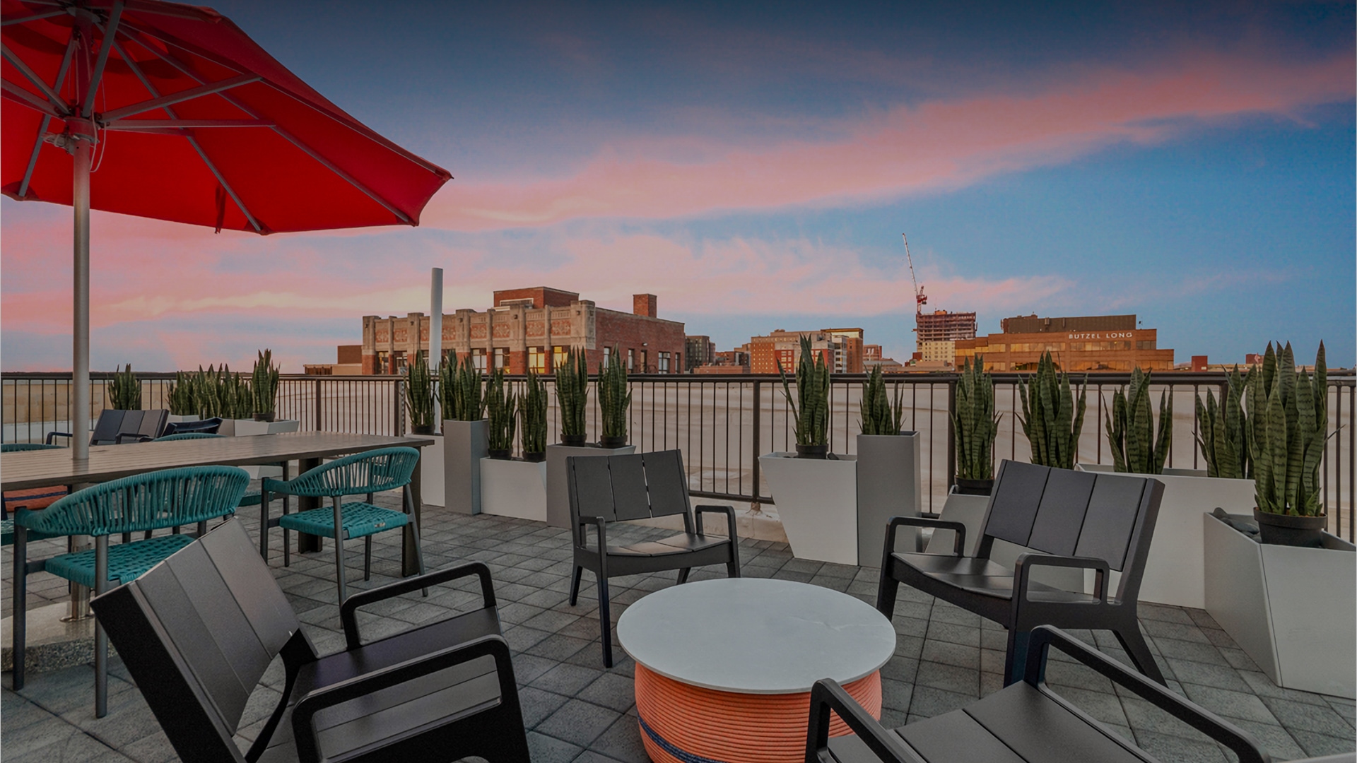 a patio with chairs and a red umbrella