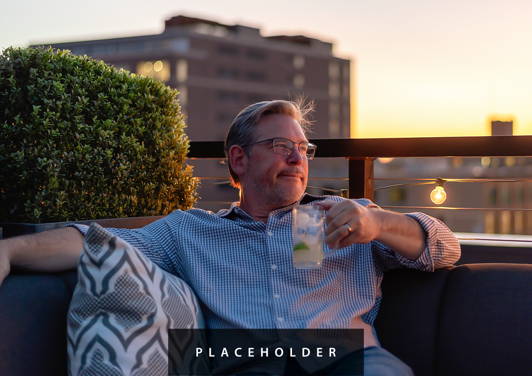 a man sitting on a bench holding a drink
