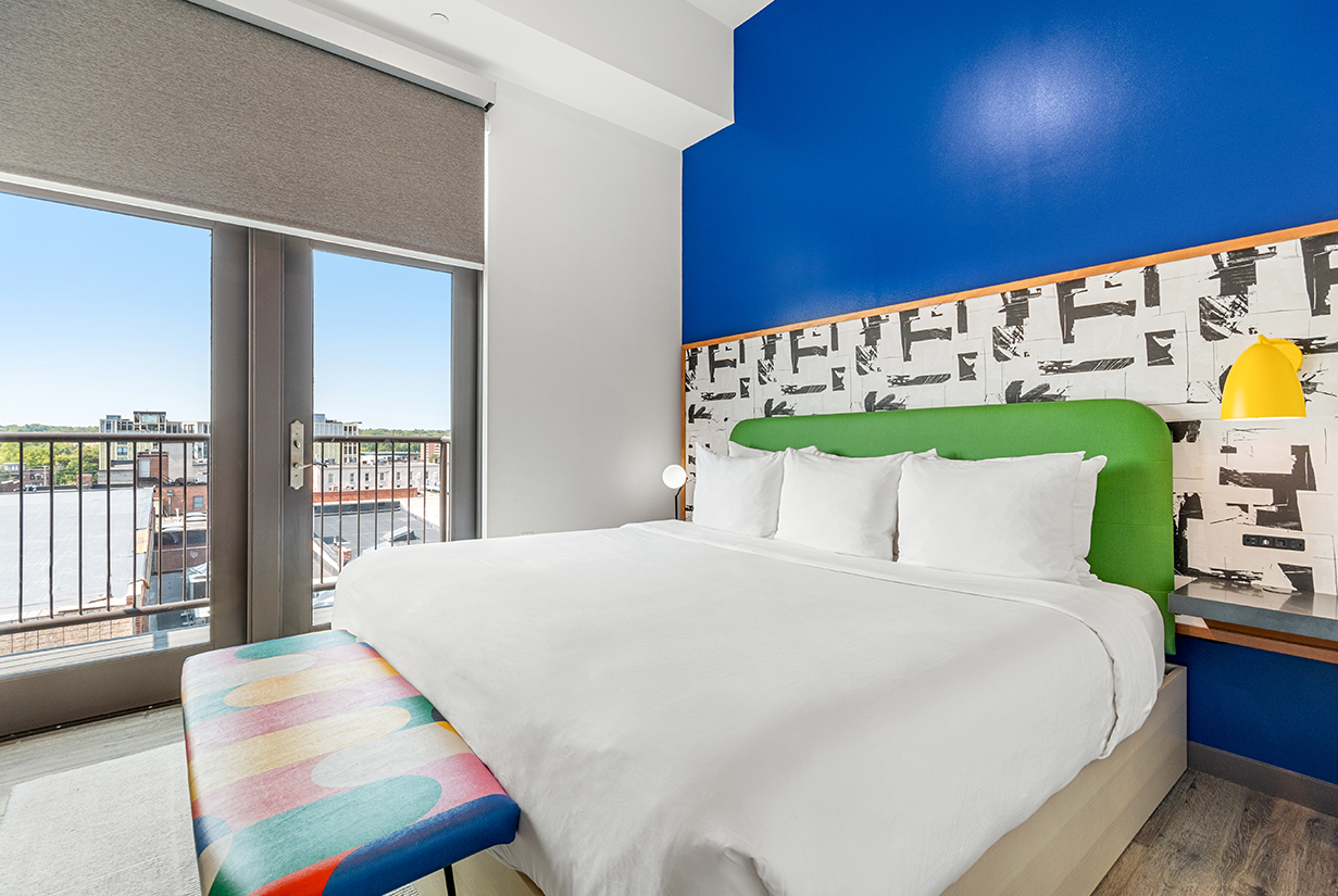 a bed with white sheets and a colorful headboard in a room