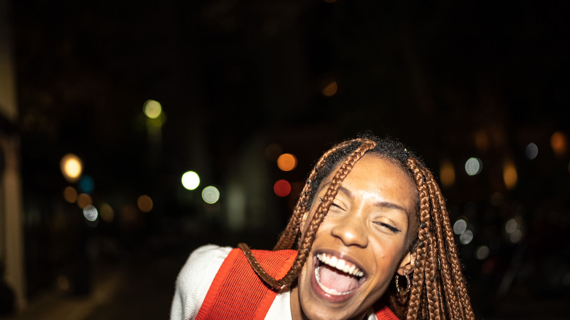 a woman with braids laughing at night
